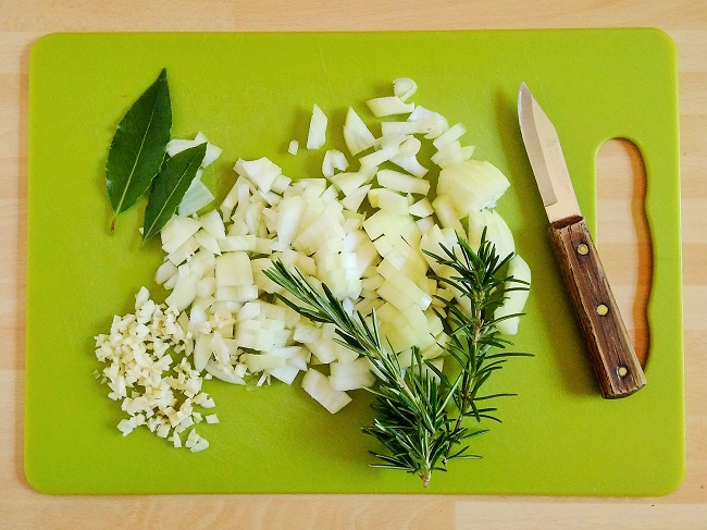 Chopping_board_with_fresh_onion_garlic_bay_and_rosemary