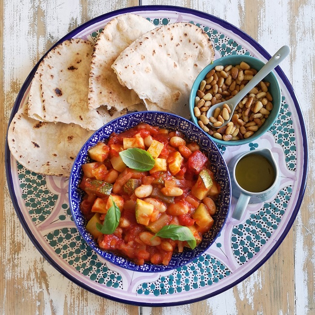 Overhead_shot_of_platter_of_courgette_and_white_bean_salad_with_flat_bread_pine_nuts_and_olive oil