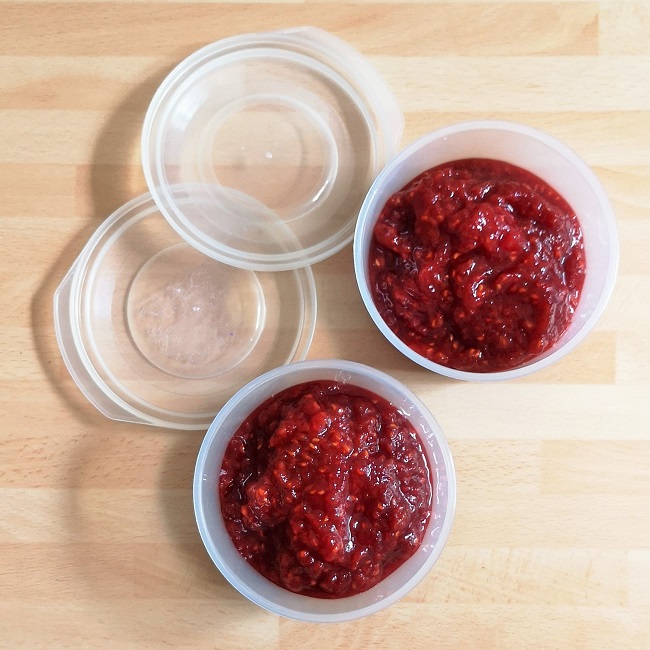 2_small_plastic_containers_of_reduced_sugar_raspberry_jam_ready_for_freezing