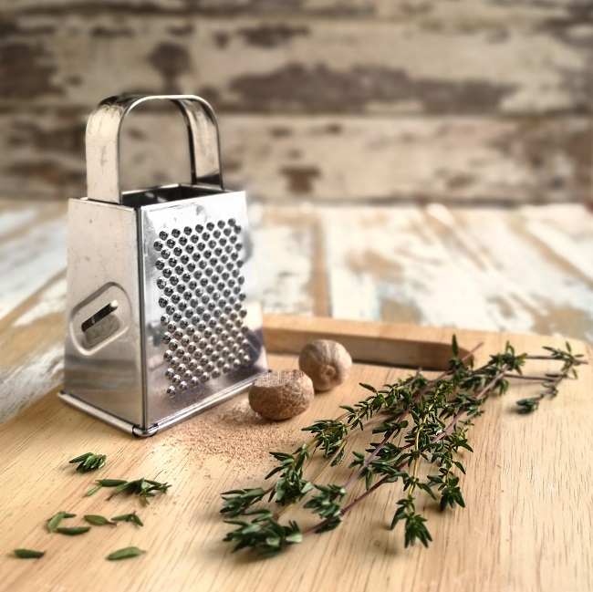 Whole_nutmeg_being_grated_alongside_fresh_thyme_sprigs