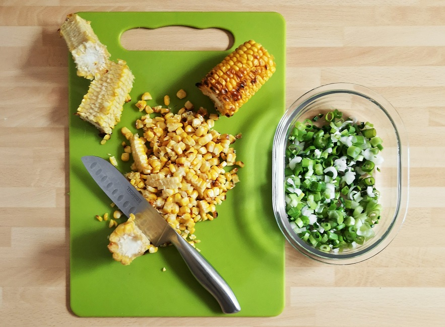 Slicing_off_cooked_sweetcorn_kernels_from_the_cobs