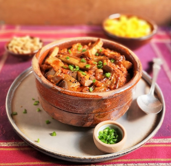 Serving_dish_of_freshly_cooked_aubergines_in_spiced_tomato_sauce