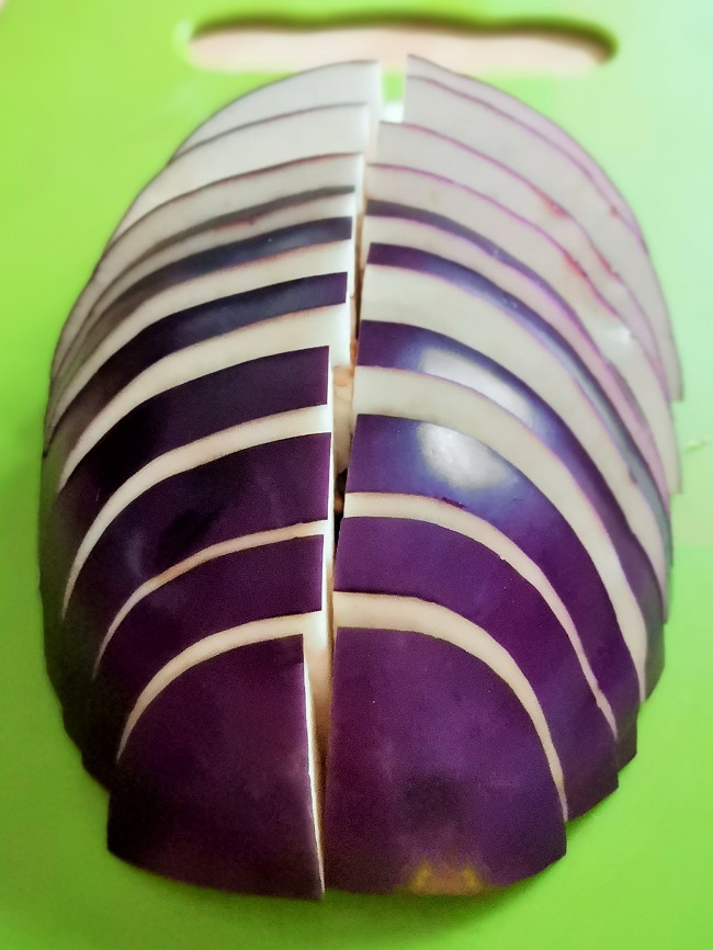 Halved_and_sliced_Italian_round_aubergine_(eggplant)_on_green_chopping_board